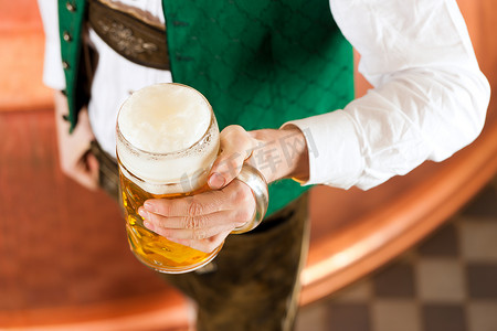 发酵罐摄影照片_啤酒厂里拿着啤酒杯的男人