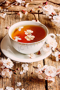 一杯茶和木制背景上的春天的花朵。