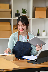 亚洲女性小企业主在数字平板电脑上确认订单或接受客户订单并使用计算器