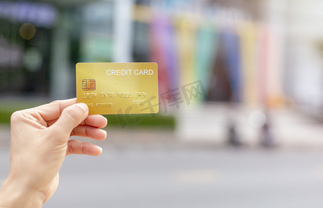妇女手持黄金信用卡会员卡在模糊的百货商店背景。