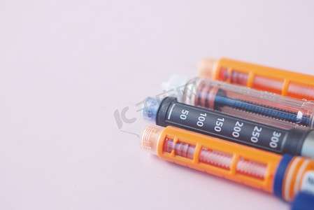 浅粉色背景中的许多胰岛素笔