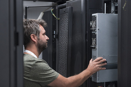 在服务器机房或数据中心工作的 IT 工程师技术人员将公司业务大型机超级计算机或 cryptocurrency 采矿场的新服务器放在机架中。