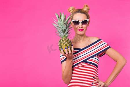 粉色菠萝摄影照片_滑稽的女人和菠萝画象在桃红色背景与copyspace。