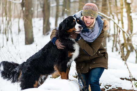 遛狗的女人摄影照片_冬天遛狗的女人一起探索雪地
