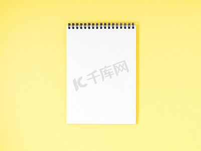黄色书桌上的空白记事本白页，彩色背景。