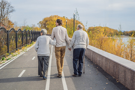 一对老年夫妇带着男助手或成年孙子在公园散步。