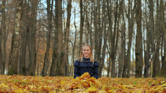 一个十几岁的女孩坐在秋天的公园里。