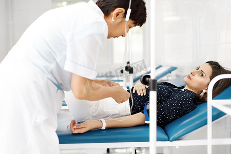 哈萨克斯坦摄影照片_哈萨克斯坦诊所病床上，护士将静脉管连接到病人的手上