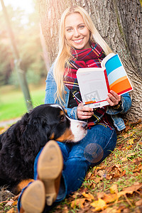 秋天公园里带着狗看书的女人