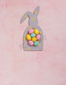 粉色圆点摄影照片_粉色混凝土背景兔形框架中的彩色圆点复活节彩蛋