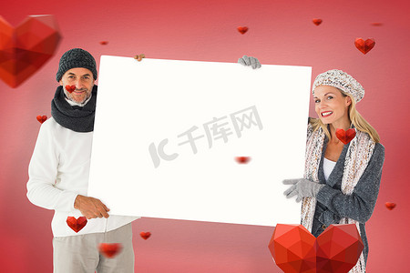 情侣海报摄影照片_冬季时尚中微笑情侣拿着海报的复合图像