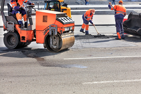道路服务摄影照片_振动溜冰场和道路推土机等小型道路设备被积极用于修补道路。