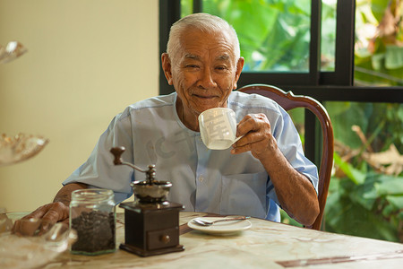 有老式咖啡研磨机的亚洲老人