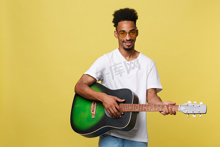 金黄色背景摄影照片_快乐的非洲裔美国音乐家在金黄色背景下用吉他合影。
