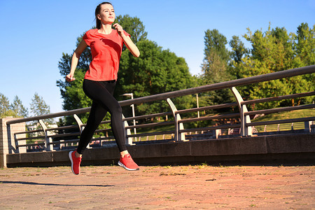 现代年轻女性穿着运动服在户外锻炼时跳跃的照片。