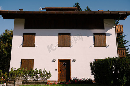 意大利威尼斯 — 2019 年 10 月 4 日：位于意大利北部、多洛米蒂山、科尔蒂纳安佩佐镇冬季滑雪胜地的一座粉刷成白色的白色房子，带有木制元素。