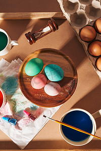 彩绘装饰摄影照片_鸡蛋、彩绘、画笔、木制背景上的铅笔、彩蛋、为复活节、春季季节性假期做准备