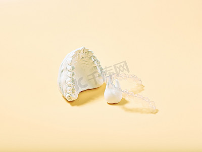 隐形牙套摄影照片_黄色背景中的正畸牙科主题。适用于正畸牙科治疗的透明隐形牙齿矫正器或牙套