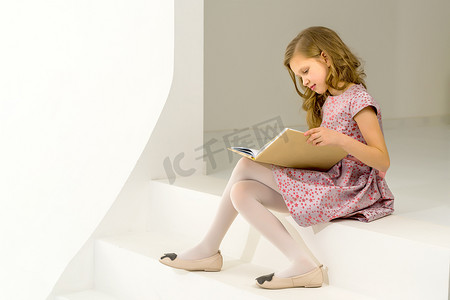 粉色台阶摄影照片_美丽的金发女孩坐在台阶上和 Int 一起看书