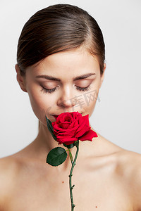 玫瑰红摄影照片_迷人的女人闭着眼睛嗅着玫瑰红的嘴唇