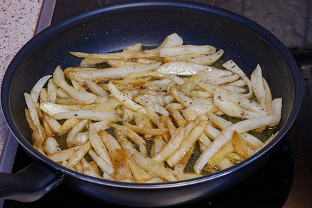 在家庭厨房用热橄榄油煎炸薯条。