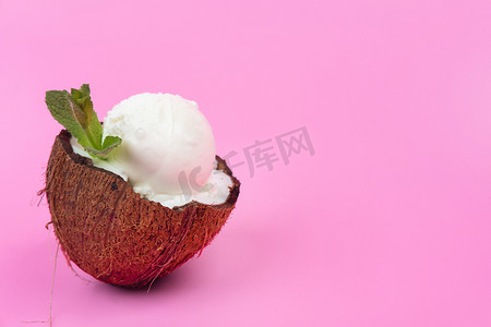 新鲜椰子半块的香草冰淇淋球，装饰着粉红色背景的薄荷叶