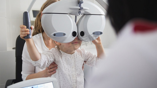 视力儿童摄影照片_儿童眼科 — 验光师检查小女孩的眼睛