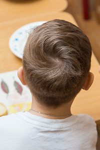 儿童理发摄影照片_男孩的后脑勺，头发盘在上面。