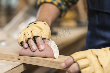 关闭男性木匠用砂纸摩擦木头。