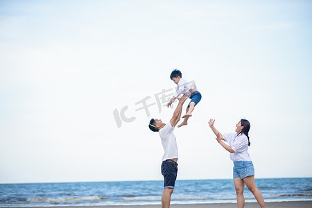 活跃的父母和人们在暑假和与孩子一起度假的户外活动。幸福的家庭和儿子在沙滩上享受日落海的乐趣。