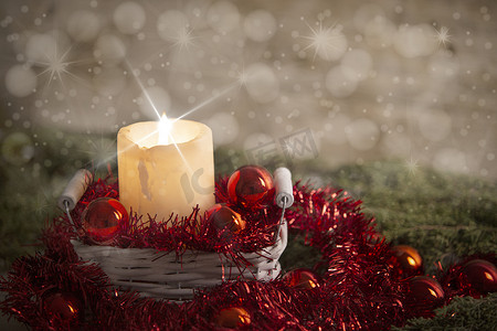 效果火焰摄影照片_圣诞概念：点燃的蜡烛点亮，十字屏星效果在白色破旧的篮子里，篮子里有红色圣诞小饰品、红色装饰花环、天然松树枝、木质背景和雪效果