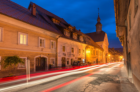 城城有家摄影照片_斯科菲亚洛卡 — 2015年4月，斯洛文尼亚：斯洛文尼亚小镇斯科菲亚洛卡的狭窄街道，有汽车灯道、历史悠久的住宅和老教堂