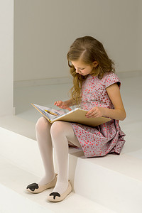 粉色台阶摄影照片_美丽的金发女孩坐在台阶上和 Int 一起看书