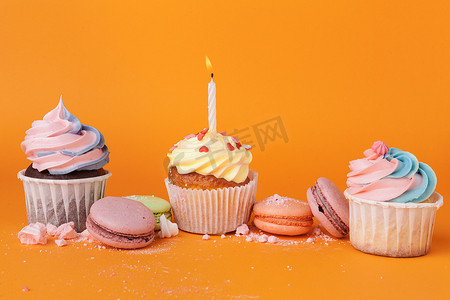 橙色背景上有生日蜡烛的纸杯蛋糕