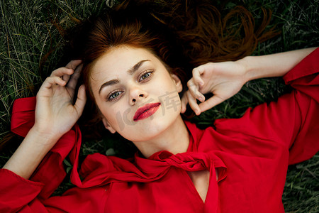 致辞摄影照片_穿红裙子的女人躺在草地上致辞时尚夏日