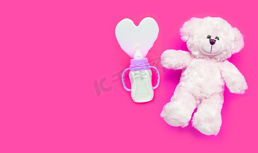 婴儿奶瓶，带有粉红色背景的玩具白熊。