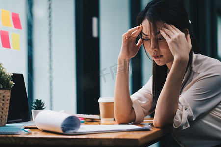 疲惫的年轻亚洲女性因工作问题而感到头痛。