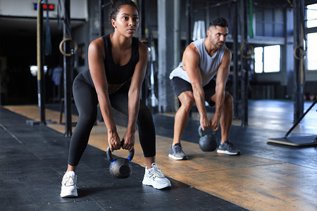 健身和肌肉发达的夫妇在健身房的运动课上专注于举哑铃。