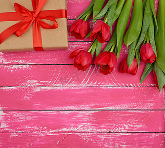 一束红色盛开的郁金香，绿叶，包裹着的礼物我