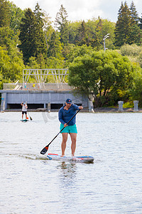 一个男人在冲浪板上游泳，用桨划水。