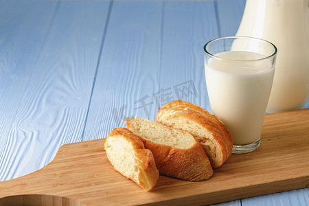 一杯牛奶杯摄影照片_木板上的一杯牛奶和切片长棍面包