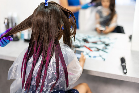 理发师在美发沙龙为一个小女孩染发。