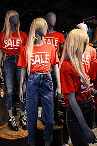 一家服装店橱窗里的人体模型，穿着带有广告销售标志的 T 恤
