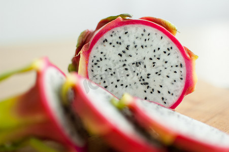 厨房木板上的火龙果或火龙果片，有粉红色的皮肤和白色的果肉，有黑色的种子。