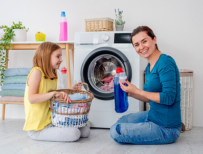 洗衣洗衣服摄影照片_快乐的妈妈和小女儿洗衣服