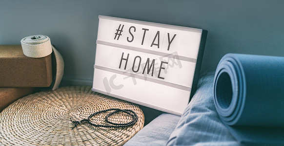 Coronavirus Yoga at Home 标志灯箱，带有文本标签 Hashtag STAYHOME，在灯光下发光，配有运动垫、软木块、带式冥想枕头。 