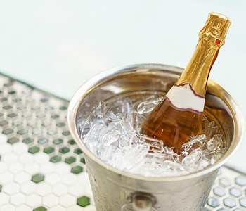 香槟干杯摄影照片_冰桶中的香槟瓶和按摩浴缸附近的两个玻璃杯