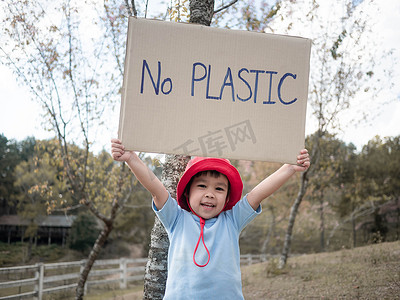 警犬标语摄影照片_小女孩举着“禁止塑料”海报，上面写着抗议森林塑料污染的标语。