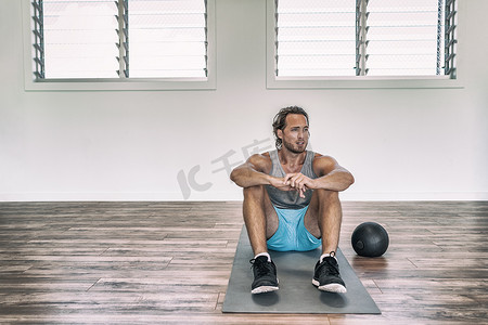 药球摄影照片_健身房锻炼男子用加重大满贯球或药球训练地板练习，休息一下，疲惫出汗，想着失望