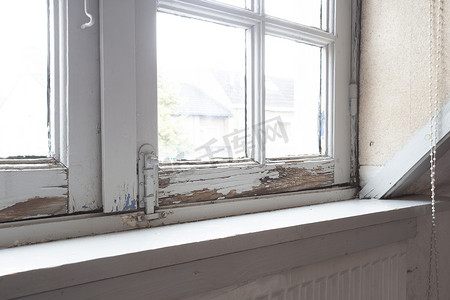 旧木窗框有腐烂的木头和开裂的剥落油漆，房子需要翻新和新框架